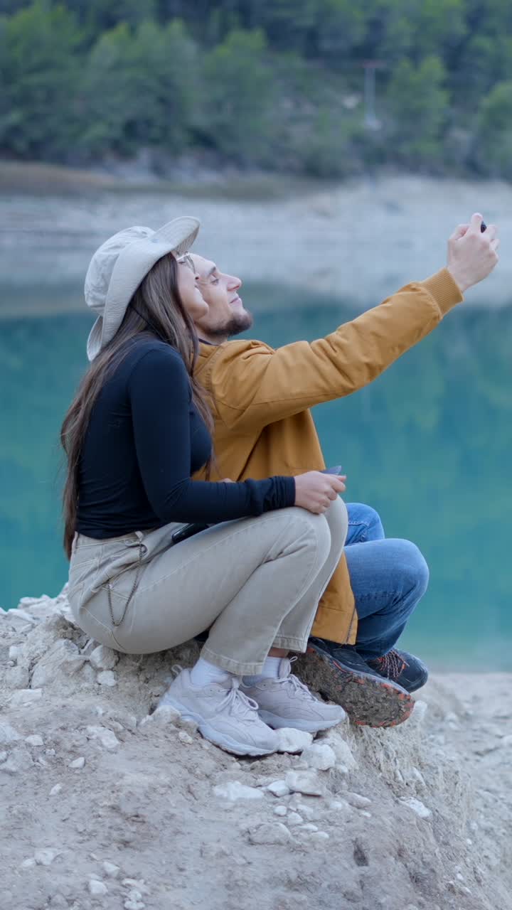 una pareja tomando una selfie junto a un lago.