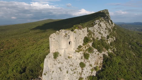 flying around a ruined castle on the edge of a mountain. aerial drone france