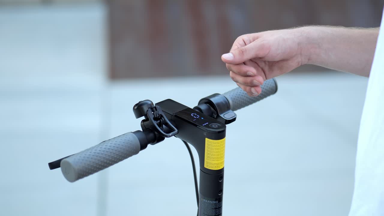 cerca de una mano de un joven empresario activando un scooter eléctrico