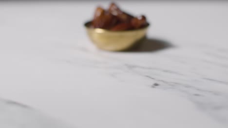 close up of bowl of dates on marble surface celebrating muslim festival of eid