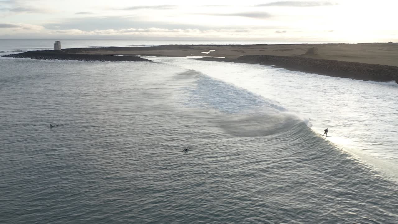 Surfista che cavalca un'onda magnifica all'alba vicino alla costa dell'Islanda meridionale, vista aerea