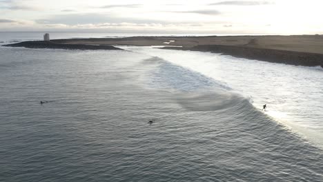 Surfer-hitting-beautiful-wave-during-sunrise-near-shore-of-South-Iceland,-aerial