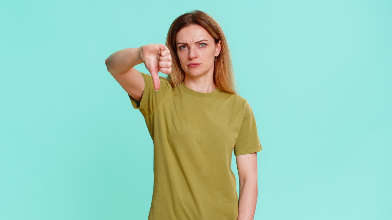 Adult woman showing thumbs down with serious face expressing dislike disapproval negative feedback