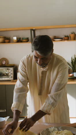 indian man making flatbread in kitchen