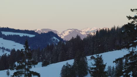 Drone-perspective-capturing-the-sunrise-over-a-silhouette-of-snow-covered-mountains