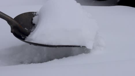 A-sidewalk-covered-in-deep-snow-is-being-cleared-using-a-large-scoop-shovel