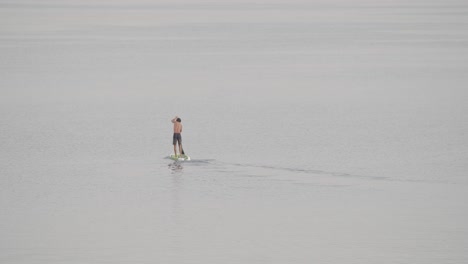 Un-Joven-En-Forma-Rema-En-Una-Tabla-De-Remo-En-Un-Mar-En-Calma-Al-Amanecer-En-Cámara-Lenta-De-60-Fps