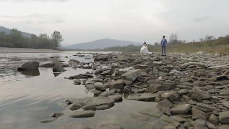 Wedding-couple-standing-near-mountain-river.-Groom-and-bride-in-love