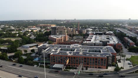 San-Antonio-Pearl-District-aerial-view-of-downtown,-pan-right-orbit-over-freeway-commuters-and-apartment-complex-near-riverwalk-in-4k