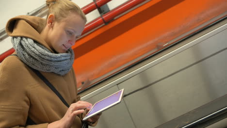 woman on escalator using tablet computer