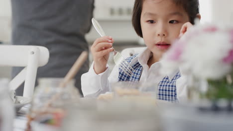 cute little asian girl eating breakfast father preparing waffles for daughter enjoying delicious homemade meal in kitchen at home getting ready for school 4k