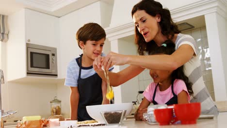 madre rompiendo el huevo en el plato mientras los niños la miran en la cocina