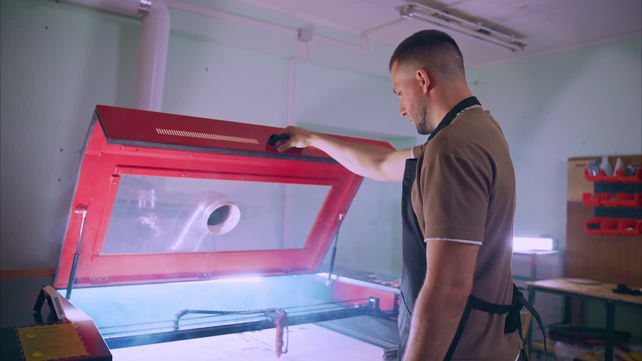 Muž obsluhující laserový řezací stroj v dílně.