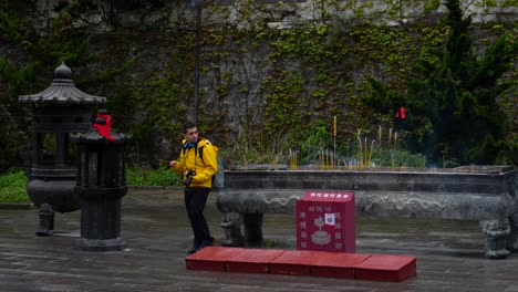 tourist with incense in tianmen temple at zhangjiajie, on a misty day, china