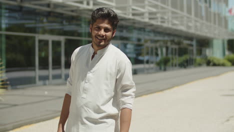 young arabian man smiling at camera on sunny day.