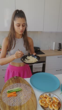 young woman preparing fresh spring rolls with rice, vegetables, and shrimp in a kitchen
