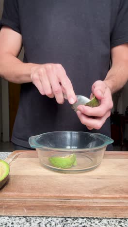 hombre quitando la pulpa de un aguacate con una cuchara