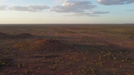 aerial shot of a car driving down a solitary road in the outback