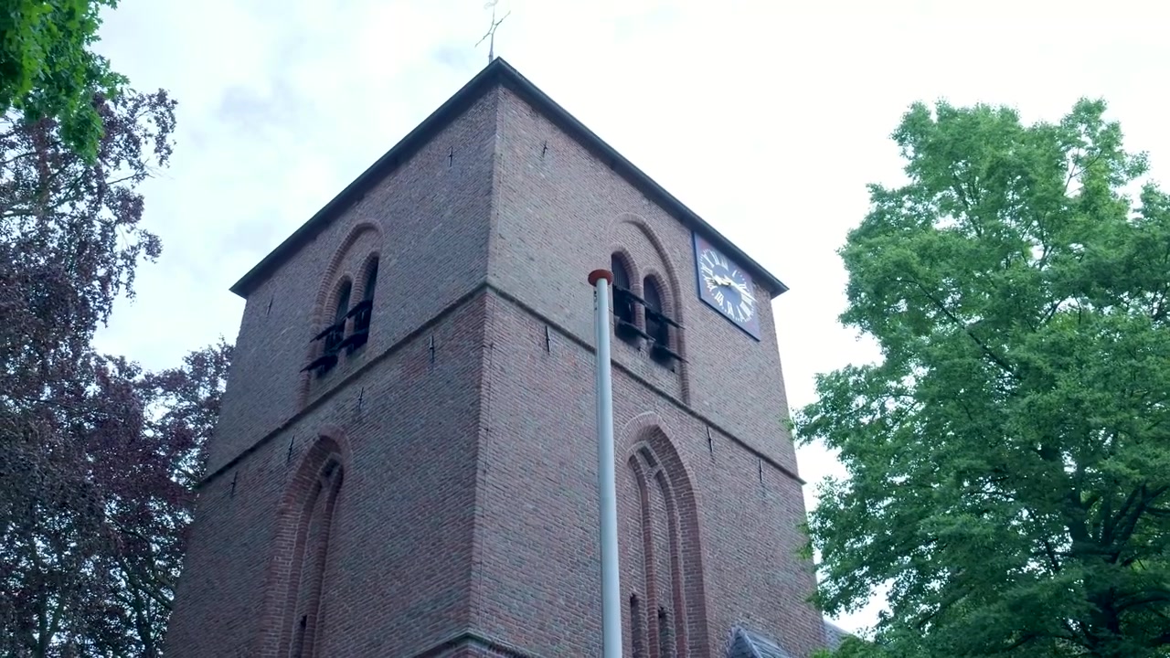 Vista de Baixo Ângulo de uma Antiga Torre de Igreja de Tijolos com Árvores Verdes