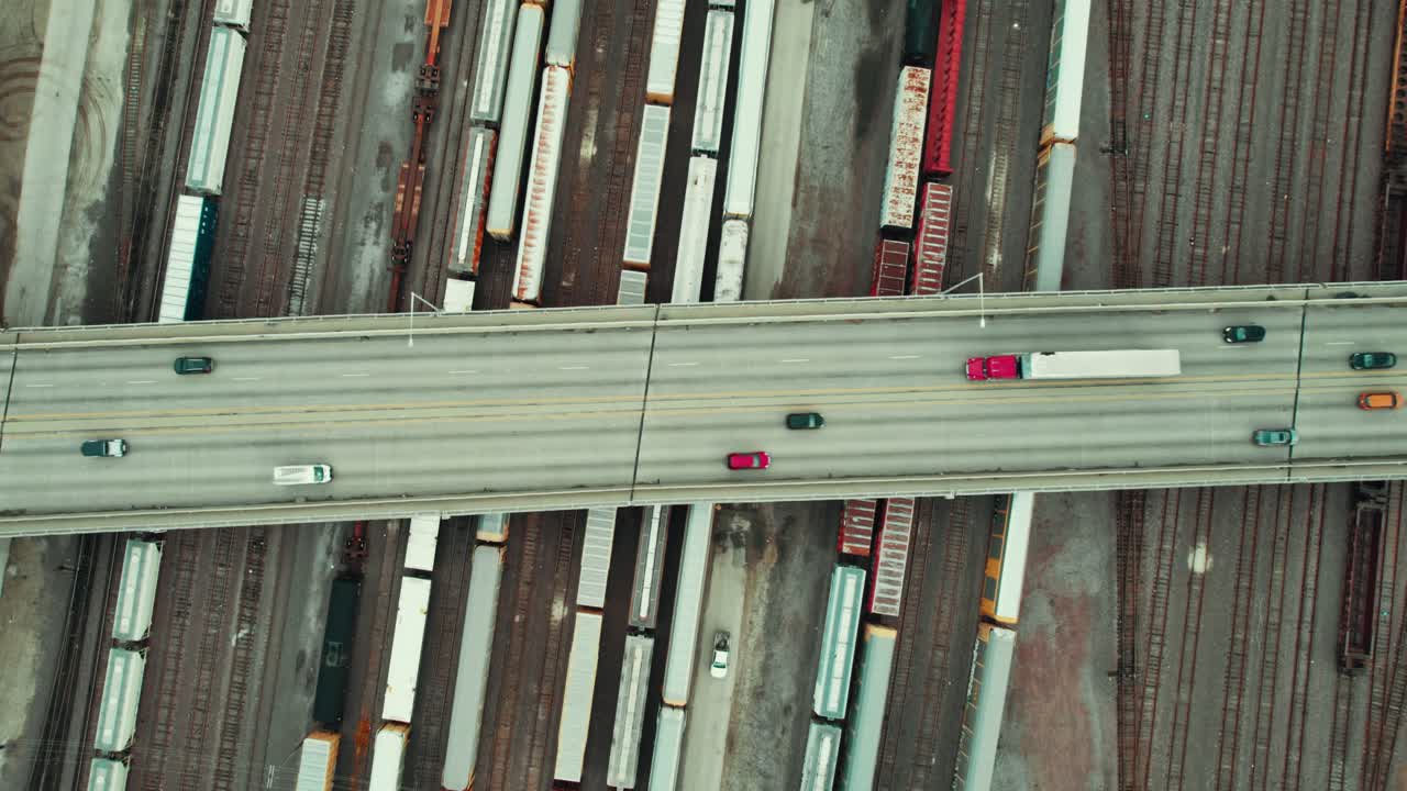 top down aerial of a bridge overpass above multiple rail roads with trains freight