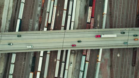 top-down-aerial-of-a-bridge-overpass-above-multiple-rail-roads-with-trains-freight