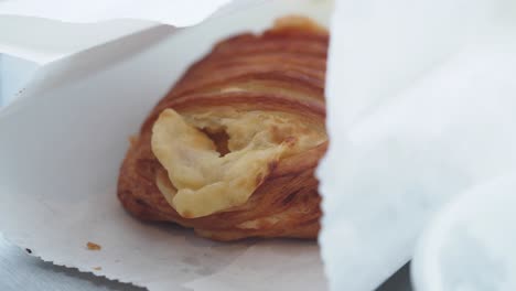 golden croissant partially wrapped in white paper
