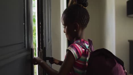 Video-De-Una-Niña-Afroamericana-Con-Una-Mochila-Abriendo-La-Puerta-De-Entrada-Y-Saliendo-De-Casa-Para-Ir-A-La-Escuela