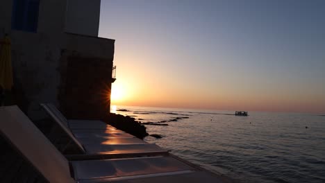 Picturesque-beach-view-of-calm-ocean-waters-and-boat-at-sunset,-Tyre,-Lebanon,-pan-right-reveal