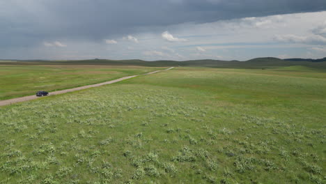 Montana-Grüne-Wildgraslandschaft-Mit-Unbefestigter-Straße,-Auf-Der-Das-Auto-Fährt