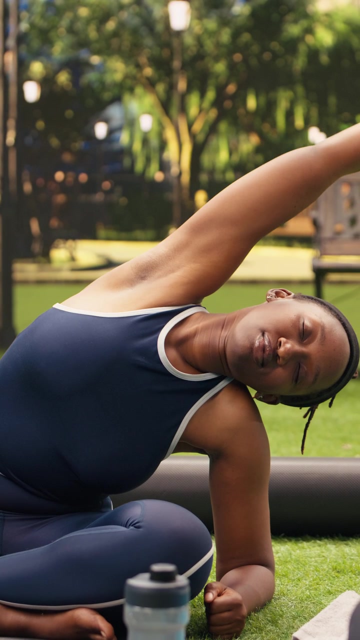 Video verticale: istruttore di yoga che mostra la posizione di flessione laterale da seduti insieme ai partecipanti