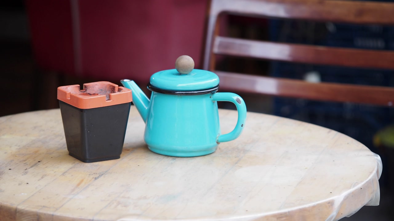 Still Life of a Turquoise Teapot and Ashtray on a Wooden Cafe Table