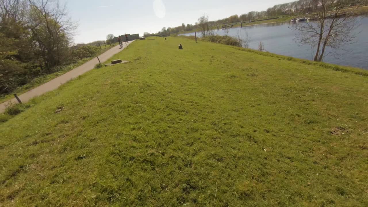 Aerial drone flight with people riding bikes by field along Veere water canal