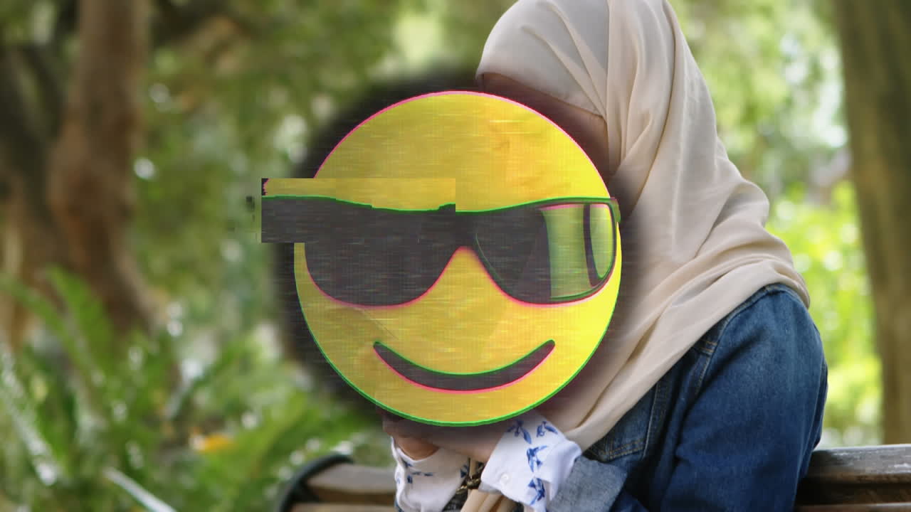 animación de un emoji feliz sobre una mujer con hijab usando un teléfono inteligente