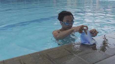 young man wearing swim goggles and cap at side of the pool then diving in the water