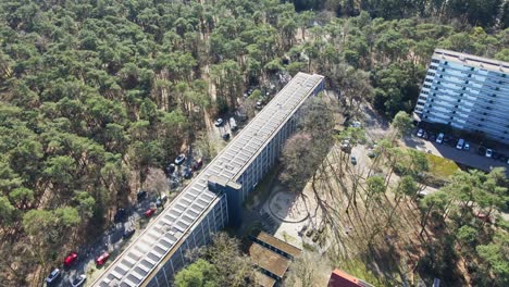aerial de un hermoso edificio de apartamentos con un techo lleno de paneles solares fotovoltaicos en un día soleado - drone volando hacia atrás