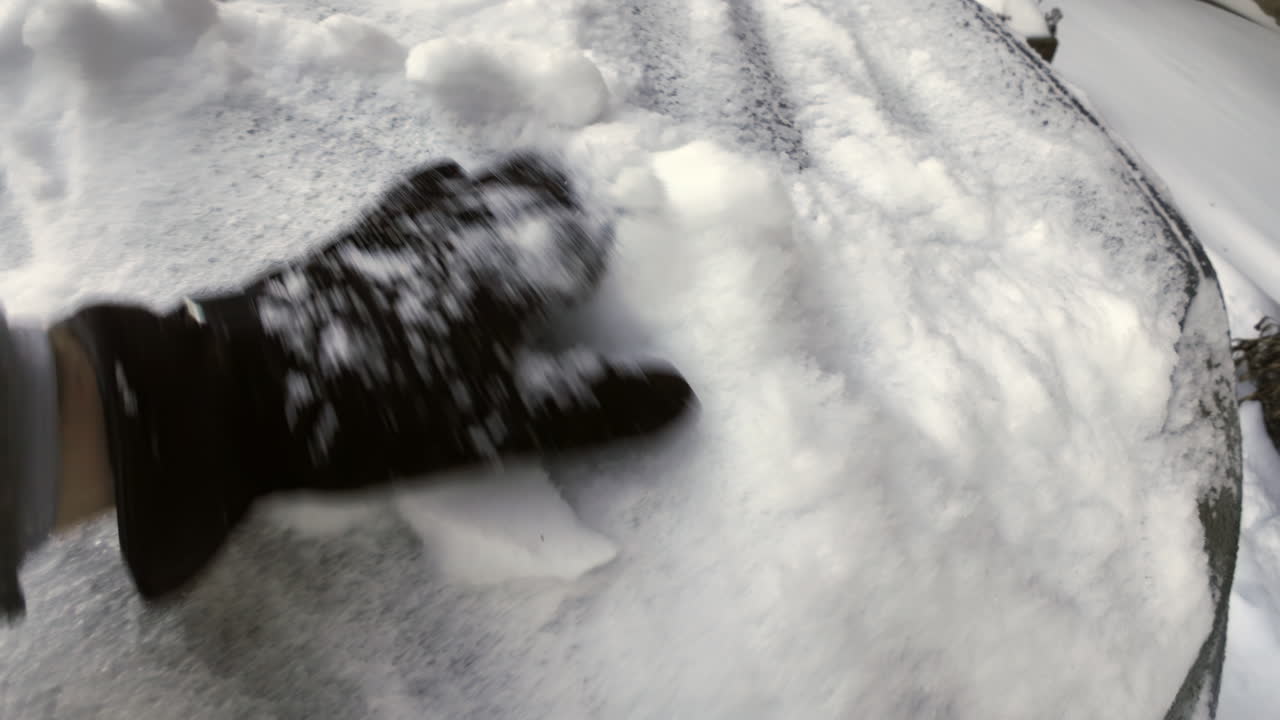 Man with brown leather gloves uncovering the car front window from frozen snow in winter