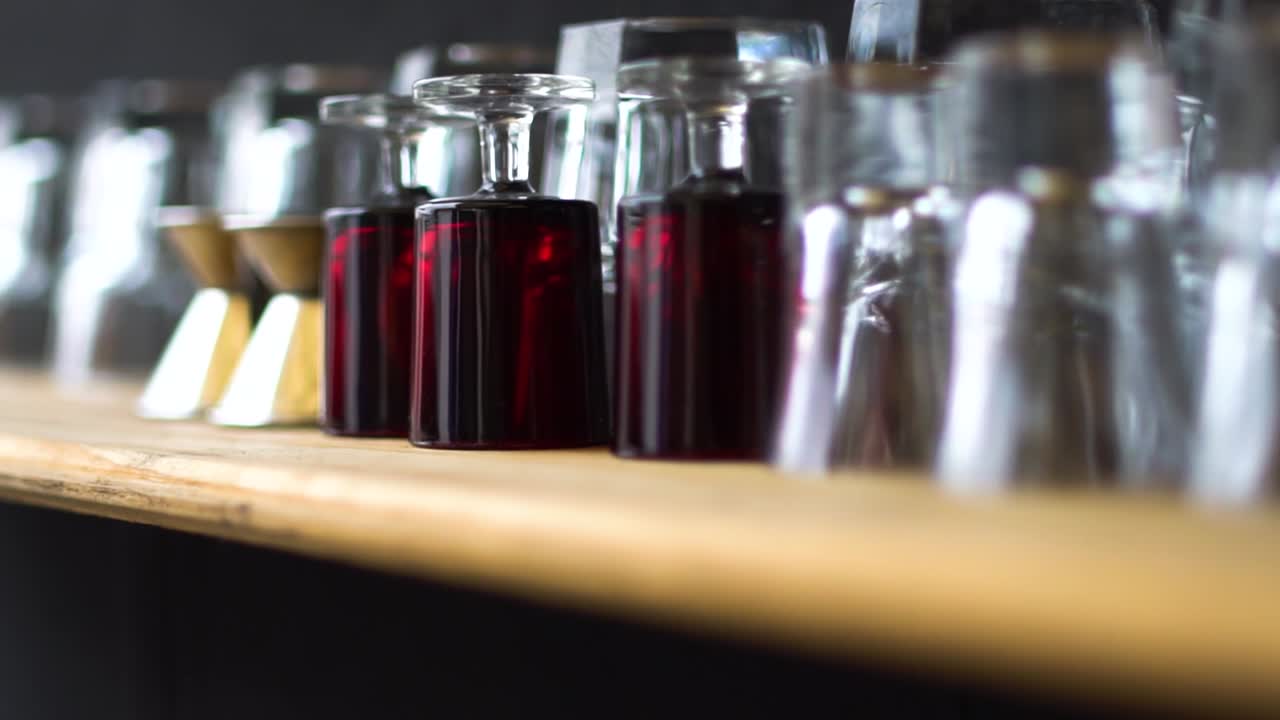 Clean Glasses Lined Upside Down On The Wooden Table In The Bar - selective focus trucking shot