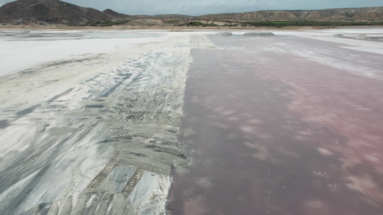 Visão aérea de escavadeira trabalhando em pilhas de sal brancas em Araya Salinas
