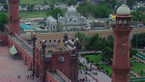 lahore, pakistán, vista aérea de la mezquita badshahi junto a los minaretes, mostrando gurdwara de los sikhs, tráfico callejero y urbano, visitantes damas, caballeros y niños están en la mezquita
