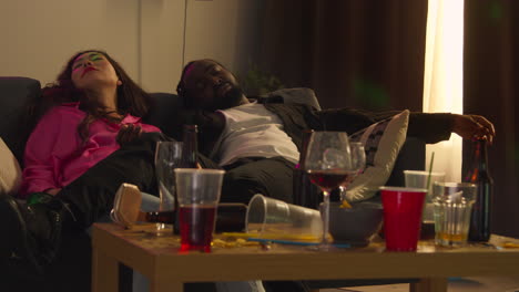 Couple-Lying-Passed-Out-On-Sofa-After-Drinking-Alcohol-At-House-Party-Suffering-With-Hangover