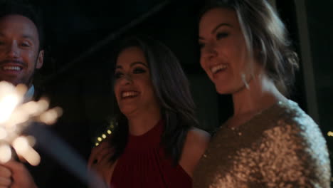 sexy group of friends at glamorous party lighting sparklers