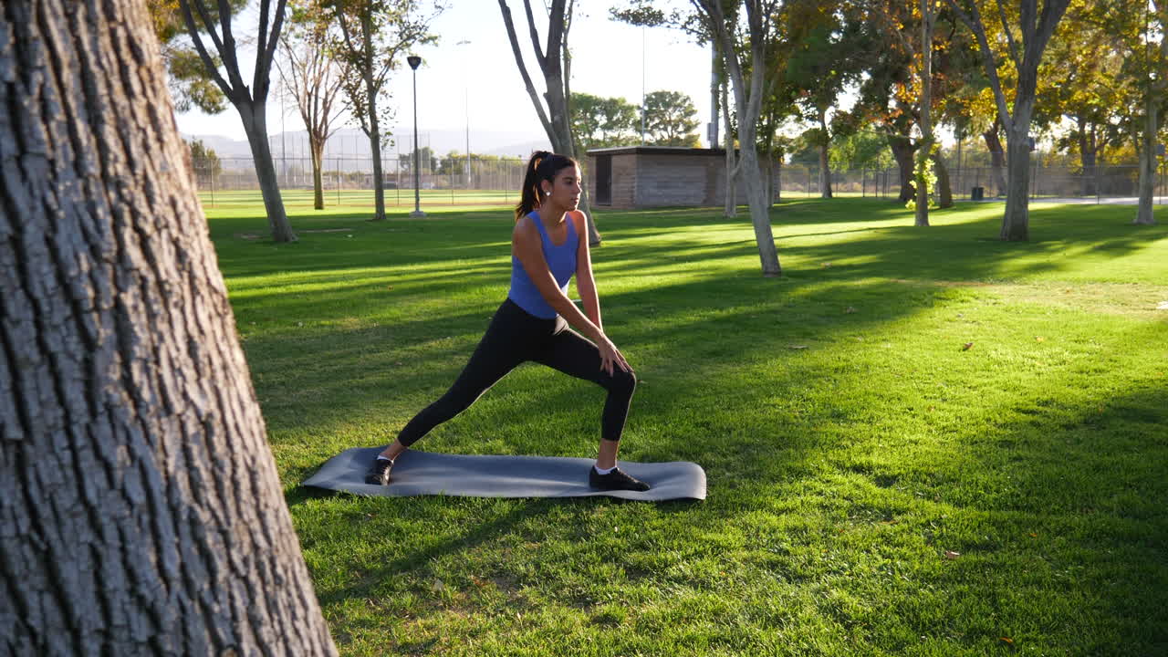 una joven sana estirando las piernas antes de hacer ejercicio en el parque al atardecer a cámara lenta