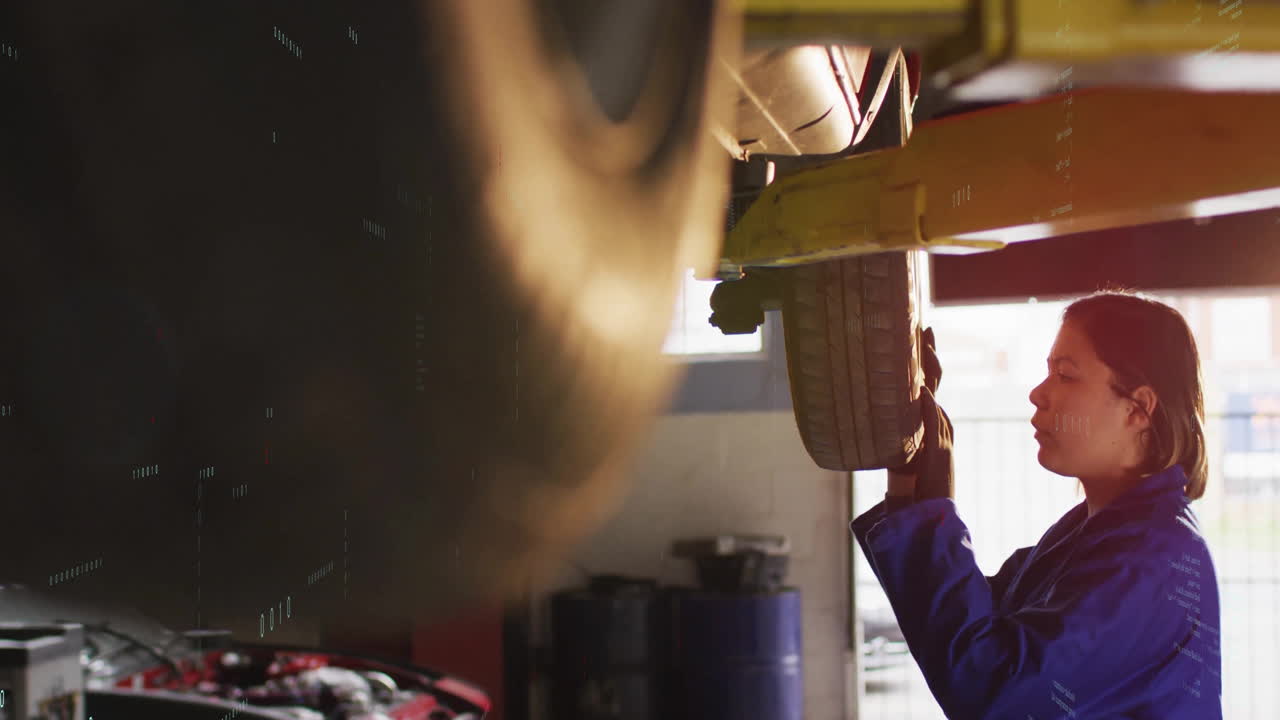 Inspecting tire on vehicle lift, mechanic in blue uniform working in garage