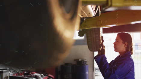 inspecting tire on vehicle lift, mechanic in blue uniform working in garage