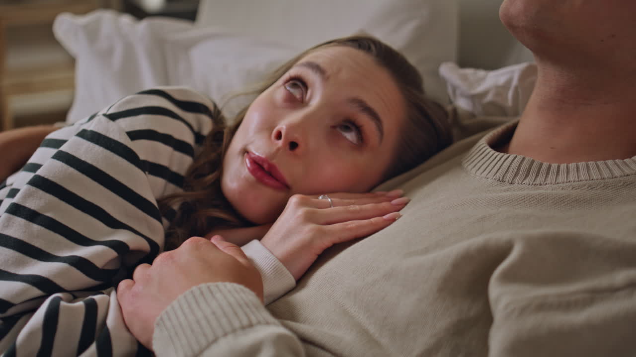 Romantic couple cuddling bed dark apartment closeup. Affectionate woman gazing