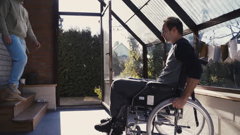 Disabled-Man-In-Wheelchair-And-His-Friend-Greeting-With-Handshake,-Hugging-Each-Other-And-Doing-Fist-Bump-At-Home