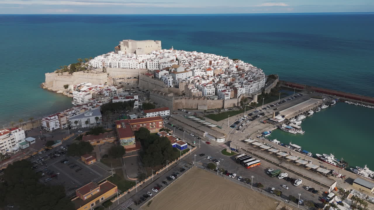 Drone flyover of Peniscola peninsula with Castell de Peniscola and marina surrounding