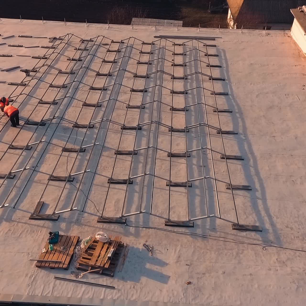New construction of solar farm on roof of building. View from above on technicians building metal basis for solar panels. Aerial view.