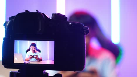 display camera of excited asian kid boy playing video game with mobile phone while live stream