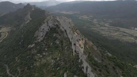 Aerial-orbits-historic-castle-ruin-high-on-limestone-cliffs-in-France